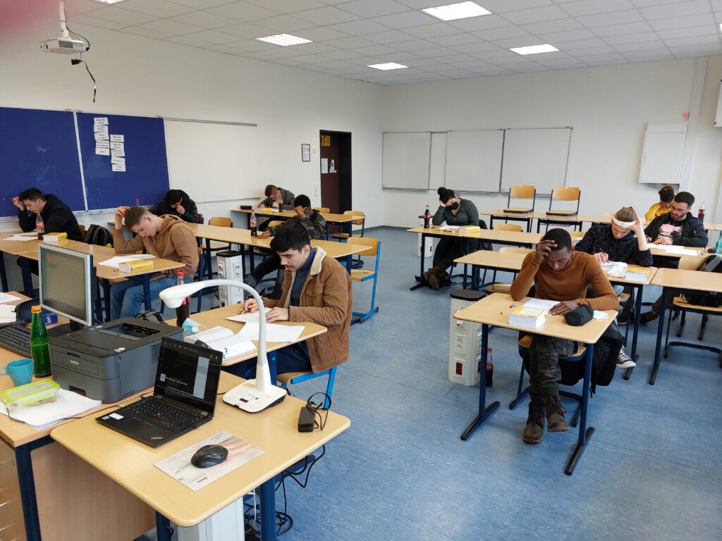 Lernende in der Prüfung, Foto des Klassenraumes.
